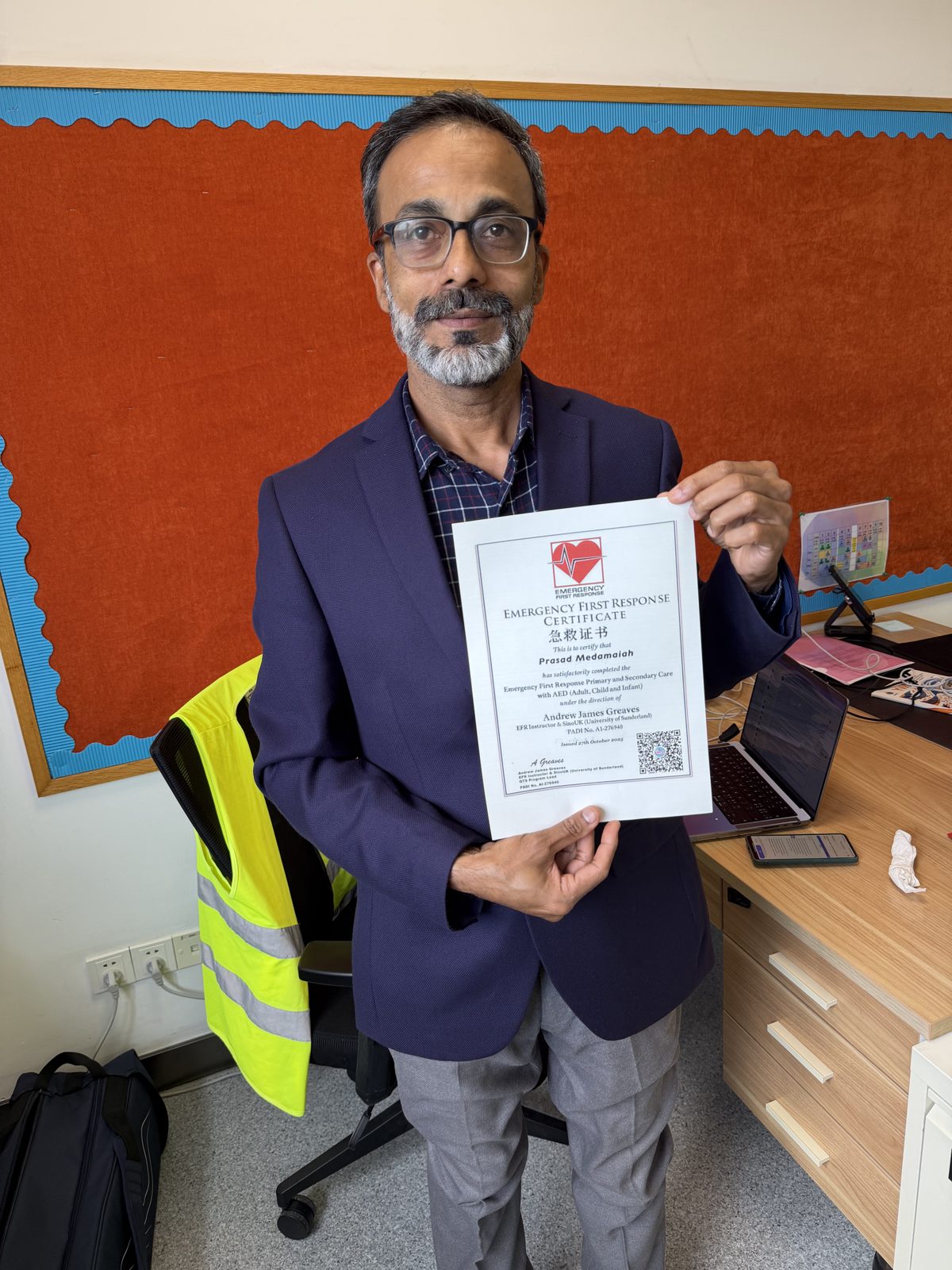 Teacher standing with UK Qualified Teacher Status certificate following successful award